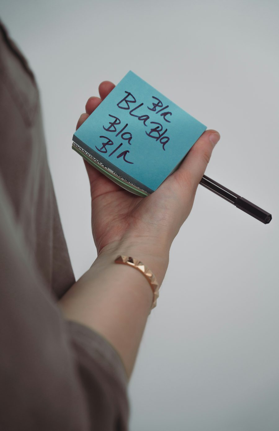 Mão segurando um bloco de post-it escrito bla bla bla